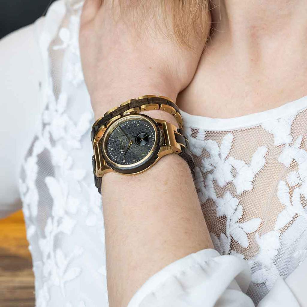 Dámske drevené hodinky Waidzeit Mystik Gold na rukách – kontrast mysticky čierneho duba a zlatej ocele vyžaruje eleganciu a silu prírody